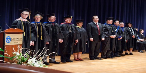 Faculty line up on stage and wait to be honored